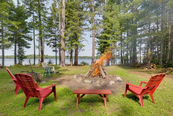 Un terrain de camping avec deux chaises rouges, une table de pique-nique et un foyer de camp.