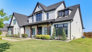 A two-story house with a large front porch, multiple windows, and a well-maintained lawn. - Luxe Retreat w/ Patio & Fenced Yard in Waxahachie! (Waxahachie)