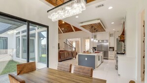 A modern kitchen with stainless steel appliances, a dining area with a wooden table and leather chairs, and a large glass sliding door leading to a patio. - Luxe Retreat w/ Patio & Fenced Yard in Waxahachie! (Waxahachie)