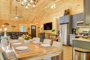 A spacious wooden cabin interior with a dining area, kitchen, and living room. - Amazing Waterfall! New Scenic Black Mtn Log Cabin (Black Mountain)