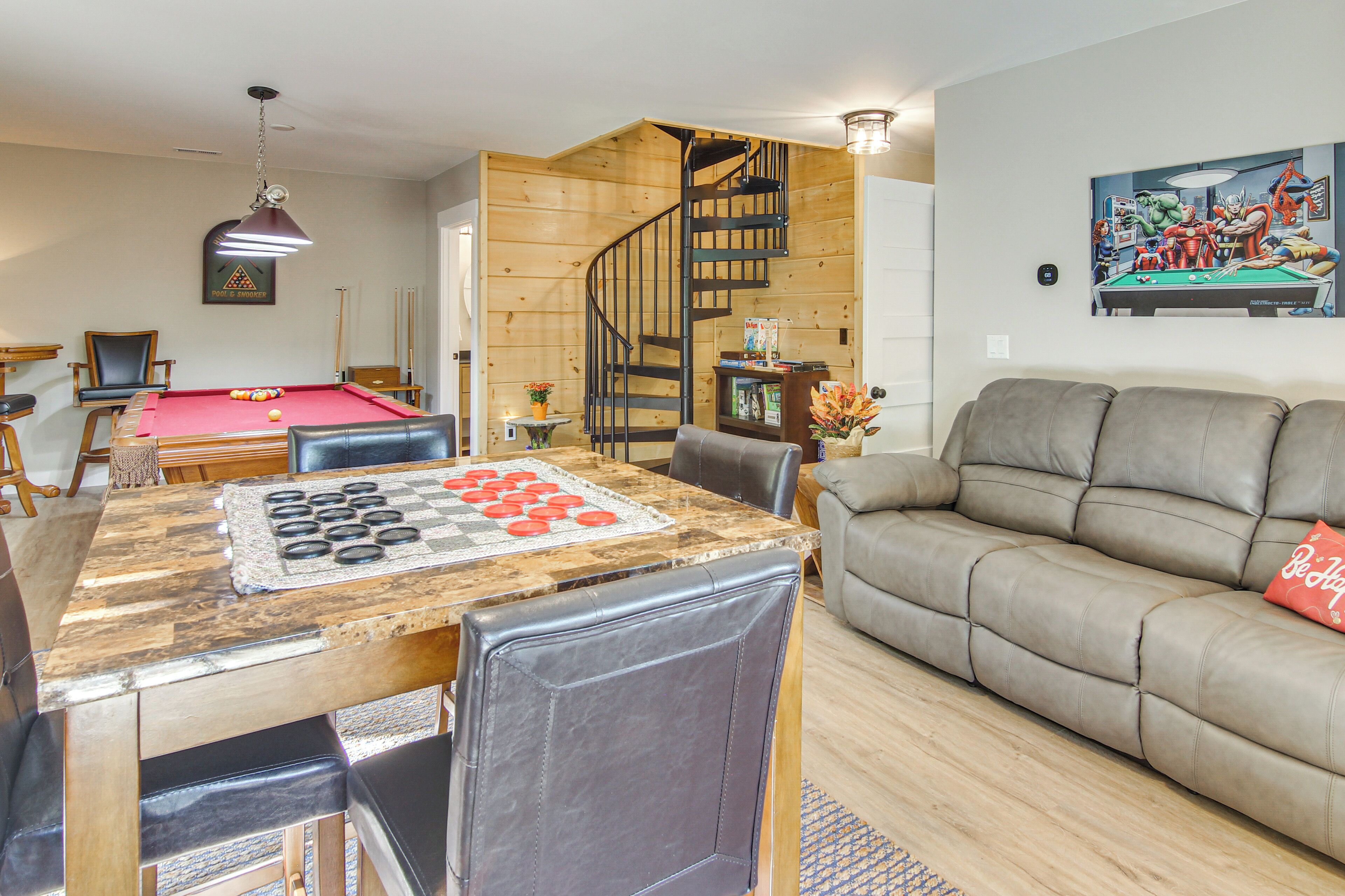 A living room with a pool table, a sofa, and a staircase.