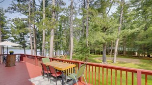 A wooden deck with a table and chairs, surrounded by a red railing, overlooking a lake and dense trees. - Lakefront Family Home w/ Dock, Views: Pet-friendly (Conover)