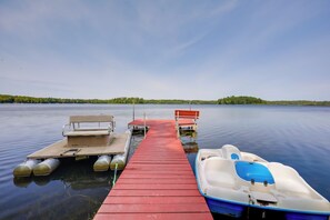 A calm lake with a wooden dock extending into the water, featuring a rowboat and a motorboat. - Lakefront Family Home w/ Dock, Views: Pet-friendly (Conover)