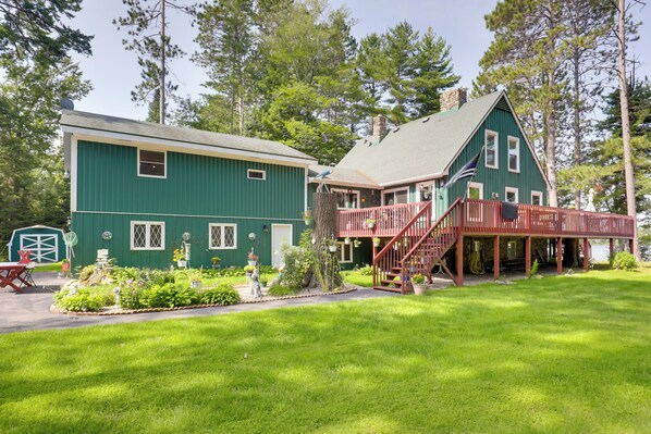A green house with a red deck and a small garden in front. - Lakefront Family Home w/ Dock, Views: Pet-friendly (Conover)