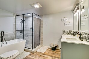 Een moderne badkamer met een douchecabine van glas, een vrijstaand bad en een wastafel met spiegel.