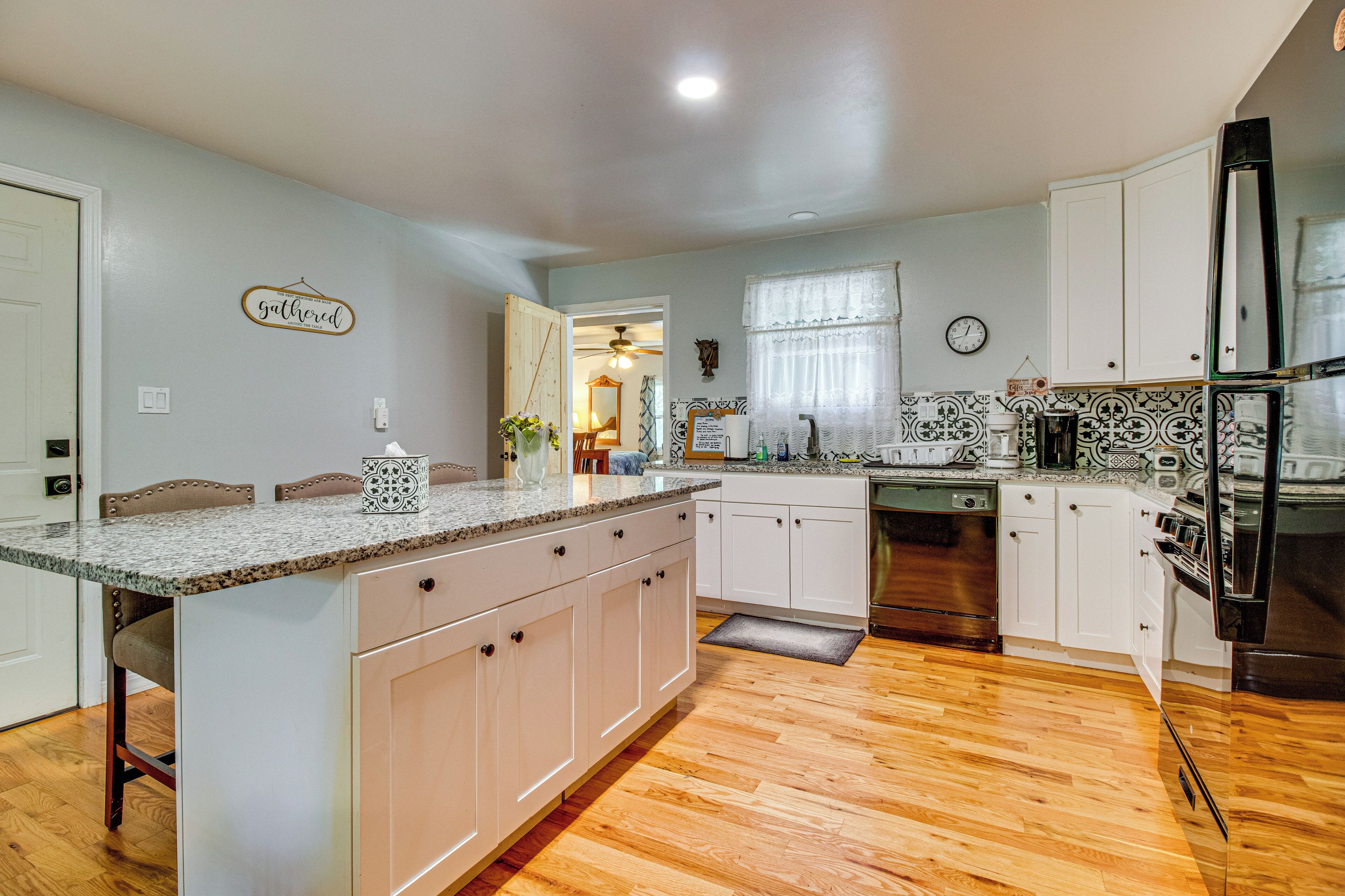 A kitchen with a central island, white cabinets, a refrigerator, and a clock on the wall.