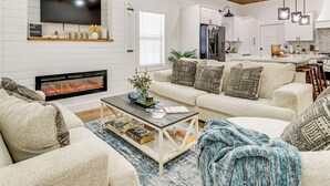 Una sala de estar moderna con chimenea, televisor de pantalla plana, un conjunto de sofás y una mesa de centro.