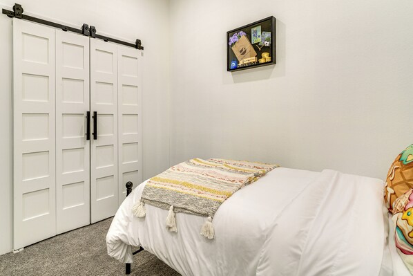 Un dormitorio con cama, televisor de pared y armario corredero.
