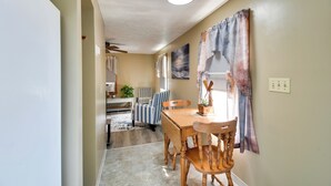 A hallway leading to a dining area with a table and chairs, a striped chair, a plant, and a ceiling fan. - Riverfront Couple's Retreat, 3 Mi to Seneca Lake! (Waterloo)