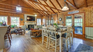 Un intérieur de cabine spacieux comprenant un coin repas, une cheminée, un plancher en bois et un ventilateur de plafond.