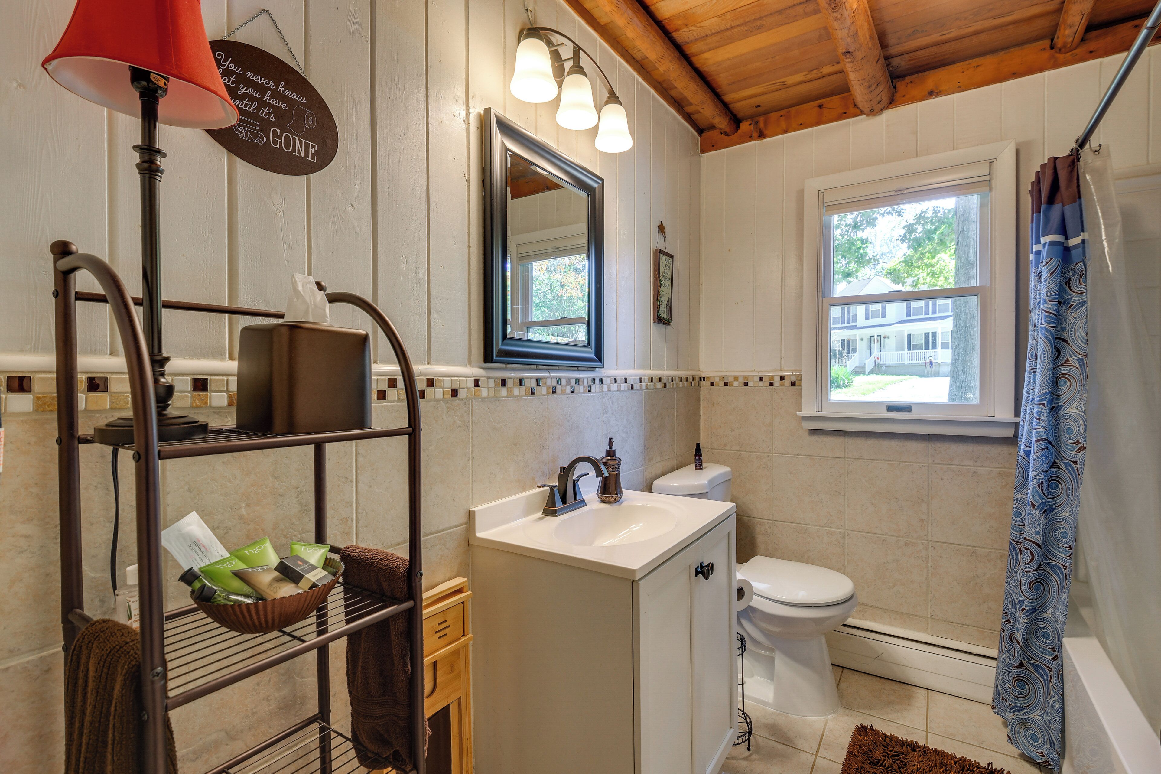 Une salle de bain avec un lavabo blanc, des toilettes, un miroir et une fenêtre.