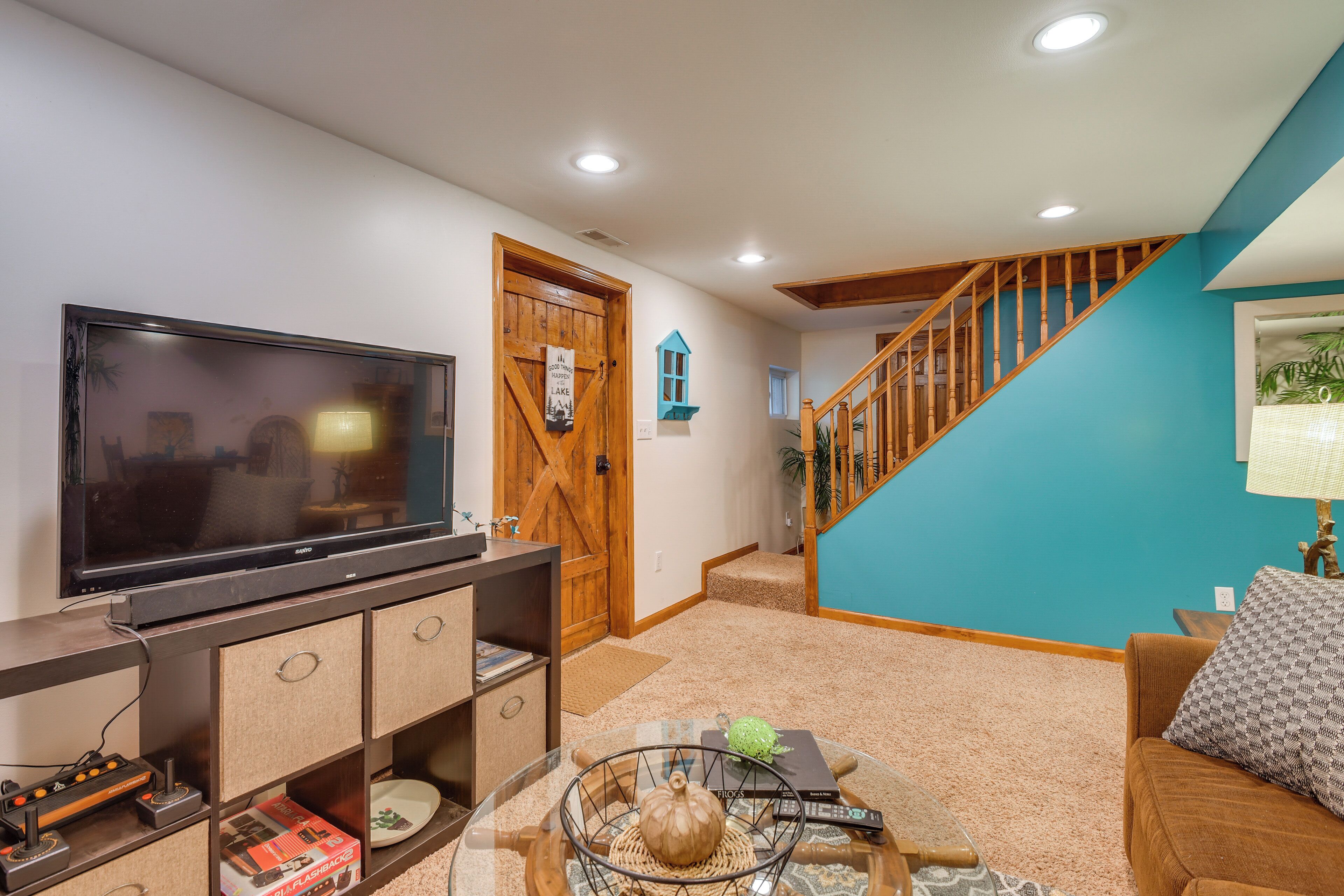 A living room with a flat-screen TV, wooden entertainment unit, and a staircase leading to a second floor.