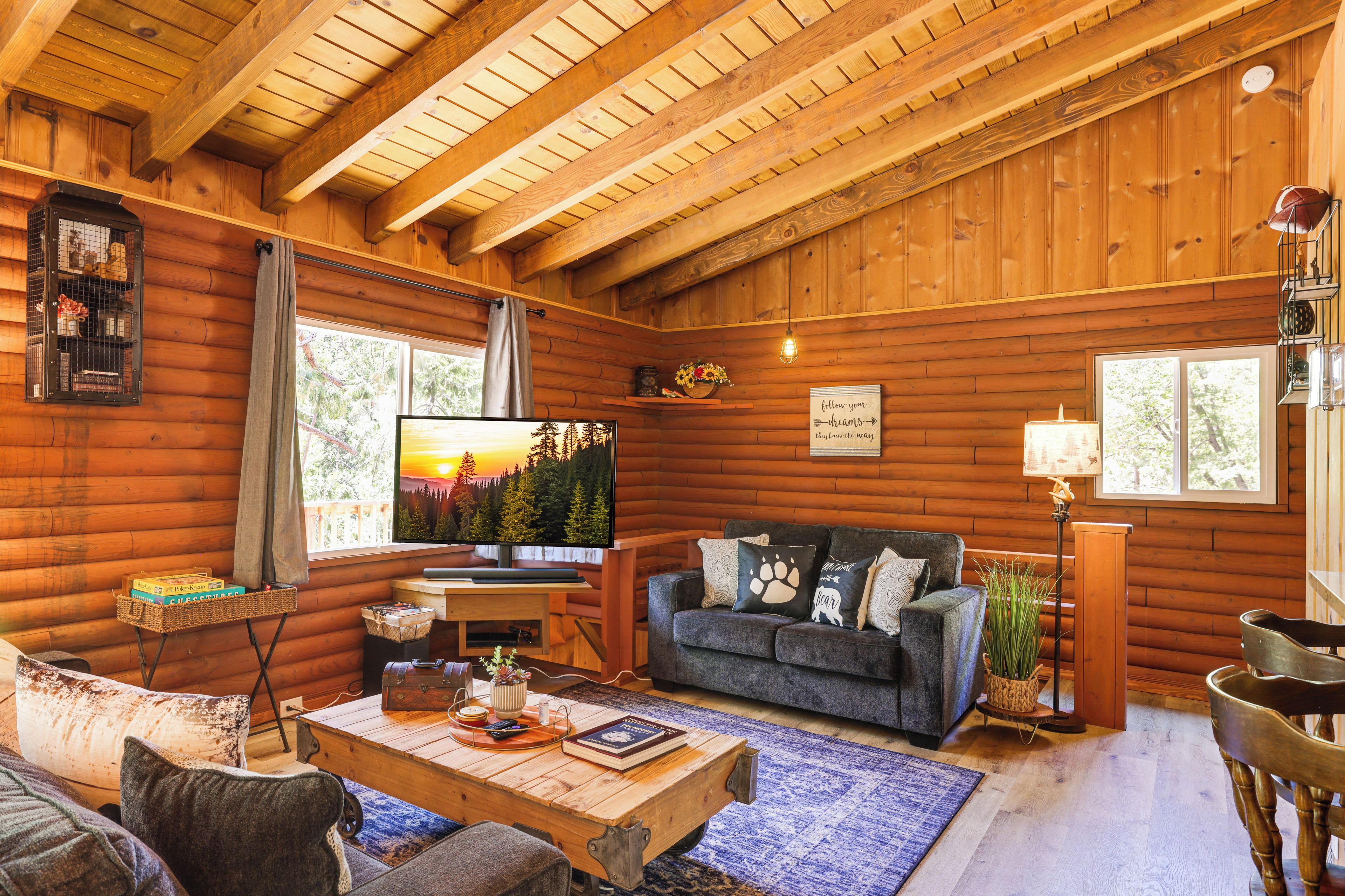 Interior acogedor de una cabaña de madera con techo de madera, un televisor, un sofá y una mesa de centro.