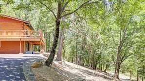 A two-story log cabin with a balcony, surrounded by dense forest. - Community Lake Access: Peaceful Cabin in Sonora! (Sonora)