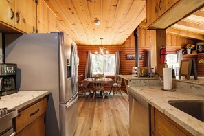 A cabin interior with a kitchen, dining area, and a view of the outdoors. - Sonora Hideaway Lake Access & Mountain Charm (Sonora)