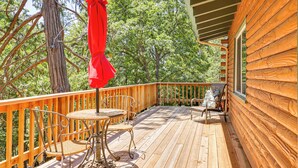 A wooden deck with a table and chairs, surrounded by a wooden railing and trees. - Community Lake Access: Peaceful Cabin in Sonora! (Sonora)