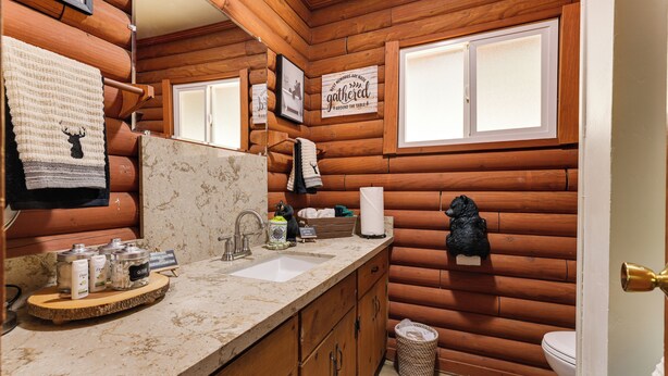 A rustic cabin-style bathroom with wooden walls, a sink with toiletries, and a mirror. - Community Lake Access: Peaceful Cabin in Sonora! (Sonora)