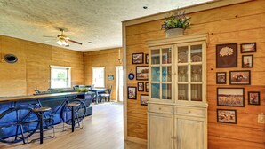 A wooden interior with a bar area, bar stools, a cabinet with glass doors, and framed pictures on the walls. - Ohio Cabin on 23 Acres: Fish, Hunt & Explore! (Lower Salem)