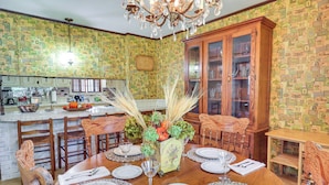 A dining area with a wooden table set for six, surrounded by chairs. There is a kitchen in the background with a white countertop and various appliances. - Rural Retreat: Cypress Lake By Roosevelt St Park (Morton)