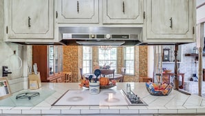 A kitchen with white cabinets, a stainless steel range hood, and a dining area with a wooden table and chairs. - Rural Retreat: Cypress Lake By Roosevelt St Park (Morton)