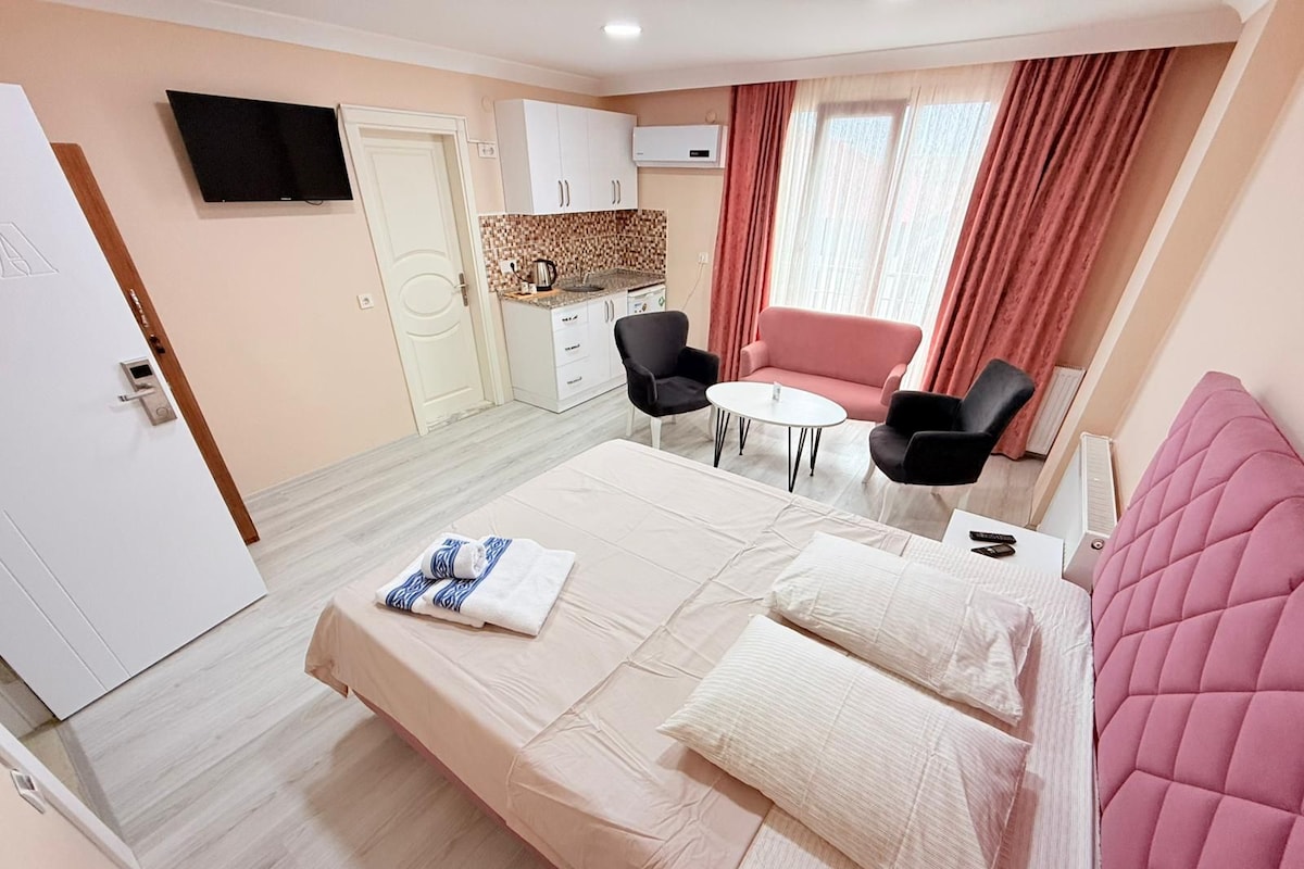 Habitación de hotel con cama, escritorio, silla, televisor y ventana con cortinas.