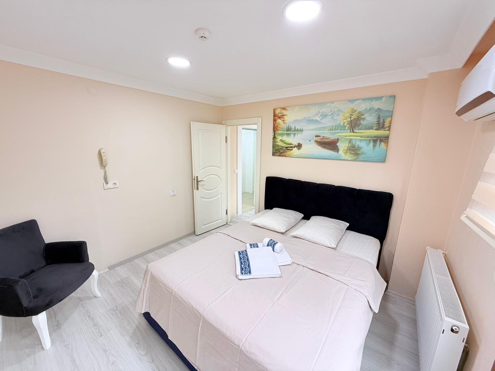 Un dormitorio con una cama, una silla, un cuadro y un radiador.