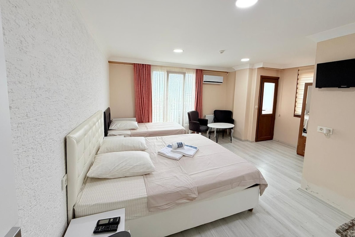 Una habitación de hotel con dos camas, una mesita, una silla y un televisor en la pared.