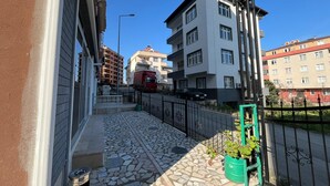 Ein Wohngebäude mit einer gepflasterten Terrasse, einem gr ünen Pflanzgefäß und einem Metallgitter.