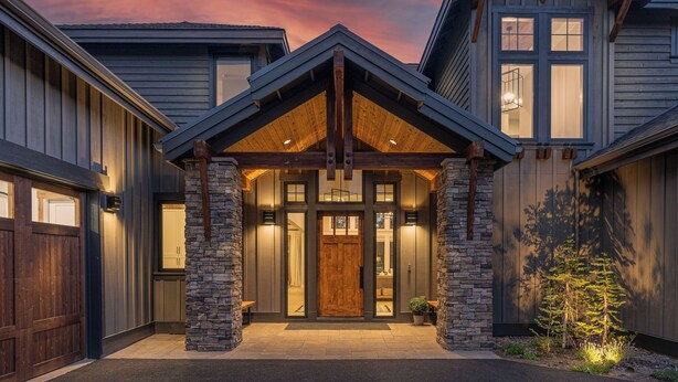 A modern house with a stone facade, a wooden front door, and a sloped roof. - Luxury Family Escape with Access to Forest House (Sunriver)
