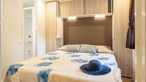 A bedroom with a bed, a hat on the bed, and a wardrobe. - Adria Holiday - Villaggio San Francesco (Caorle)