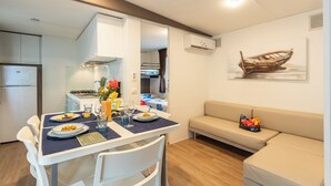 A compact living space with a kitchenette, dining area, and a sofa. - Adria Holiday - Villaggio San Francesco (Caorle)