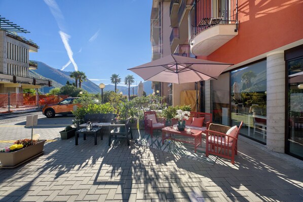 An outdoor patio with seating, a large umbrella, and a mountain view.