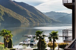 A marina with boats docked, surrounded by hills and palm trees. - Room '4' with Lake View, Wi-Fi and Air Conditioning (Porlezza)