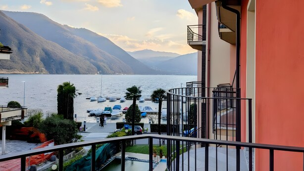 Ein Balkon mit Blick auf einen See, Boote und Berge.