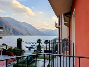 Un balcone con vista su un lago, barche e montagne.