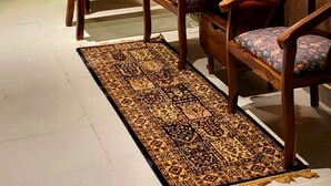 A cozy seating area with a wooden table, two chairs, a patterned rug, and a decorative wall piece. - Jaltara Stays @ Bapu Nagar, Jaipur 3BHK Apartment (Jaipur)