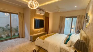 A modern bedroom with a large bed, a TV mounted on the wall, and a ceiling fan. - Jaltara Stays @ Bapu Nagar, Jaipur 3BHK Apartment (Jaipur)