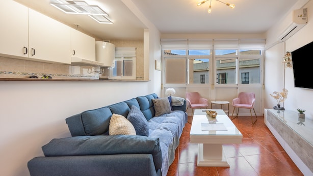 A modern living room with a sofa, coffee table, and a TV mounted on the wall. - La Justicia Apartment with Private Parking, Shared Terrace, Wi-Fi & Air Conditioning (Jerez de la Frontera)