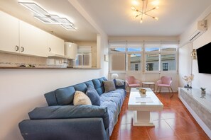 A modern living room with a sofa, coffee table, and a TV mounted on the wall.