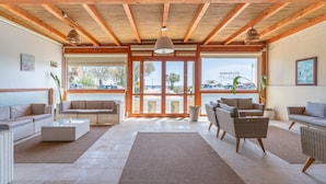 A spacious living area with wicker furniture, a large rug, and a view through glass doors to an outdoor area.