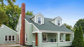 A two-story house with a green exterior, a brick chimney, and a small porch with two chairs. - Movie Theater, Game room, 4BR near Spooky Nook (Hamilton)