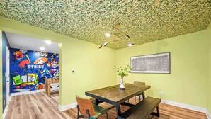 A dining area with a wooden table, chairs, and a bench. The walls are painted green, and there's a ceiling with a leafy pattern. - Movie Theater, Game room, 4BR near Spooky Nook (Hamilton)