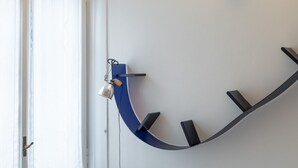 A wall-mounted, curved black shelf with a bell and a small lamp. - Studio apartment a stone's throw from CityLife (Milano)