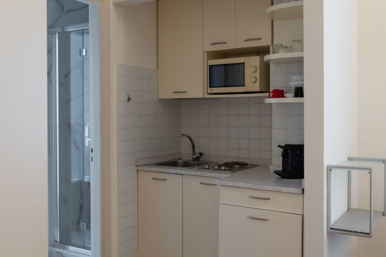 A compact kitchen with a microwave, sink, and cabinets.