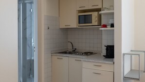 A compact kitchen with a microwave, sink, and cabinets. - Studio apartment a stone's throw from CityLife (Milano)