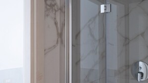 A glass-enclosed shower with a marble wall and a modern faucet. - Studio apartment a stone's throw from CityLife (Milano)