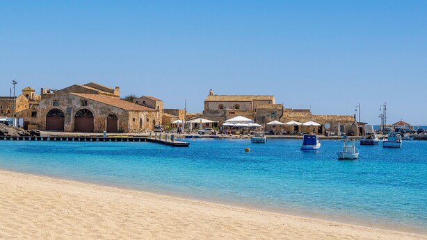 A coastal town with historic buildings, a sandy beach, and boats in the water. - Room 106 at 'Le Saline Rooms Marzamemi' with Wi-Fi and Air Conditioning (Marzamemi)