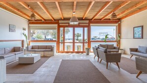 A spacious living area with wicker furniture, a large rug, and a view through glass doors to an outdoor area. - Room 106 at 'Le Saline Rooms Marzamemi' with Wi-Fi and Air Conditioning (Marzamemi)