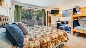 A cozy bedroom with a large bed, a bunk bed, a fireplace, and a view of the outdoors. - Tahoe condo across from Heavenly Stagecoach Lodge- (Stateline)