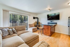 Een moderne woonkamer met een hoekbank, een open haard en een keukenhoek met een flatscreen televisie.